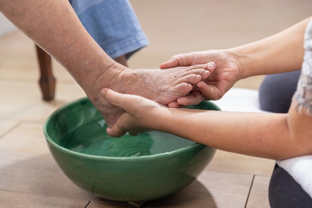 female,caregiver,wipes,the,elderly,woman,feet,by,towel.